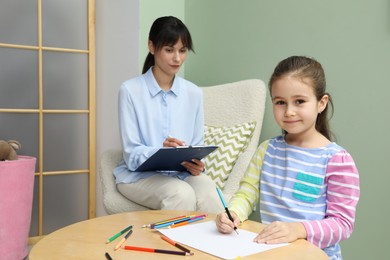 Photo of Little girl drawing during psychological evaluation in office