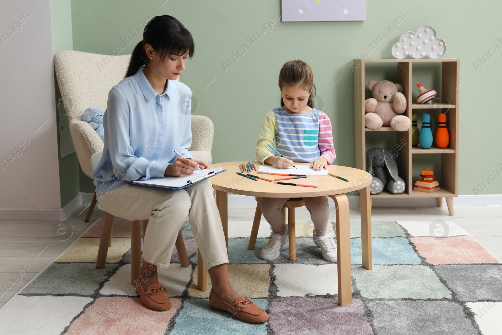 Photo of Little girl drawing during psychological evaluation in office