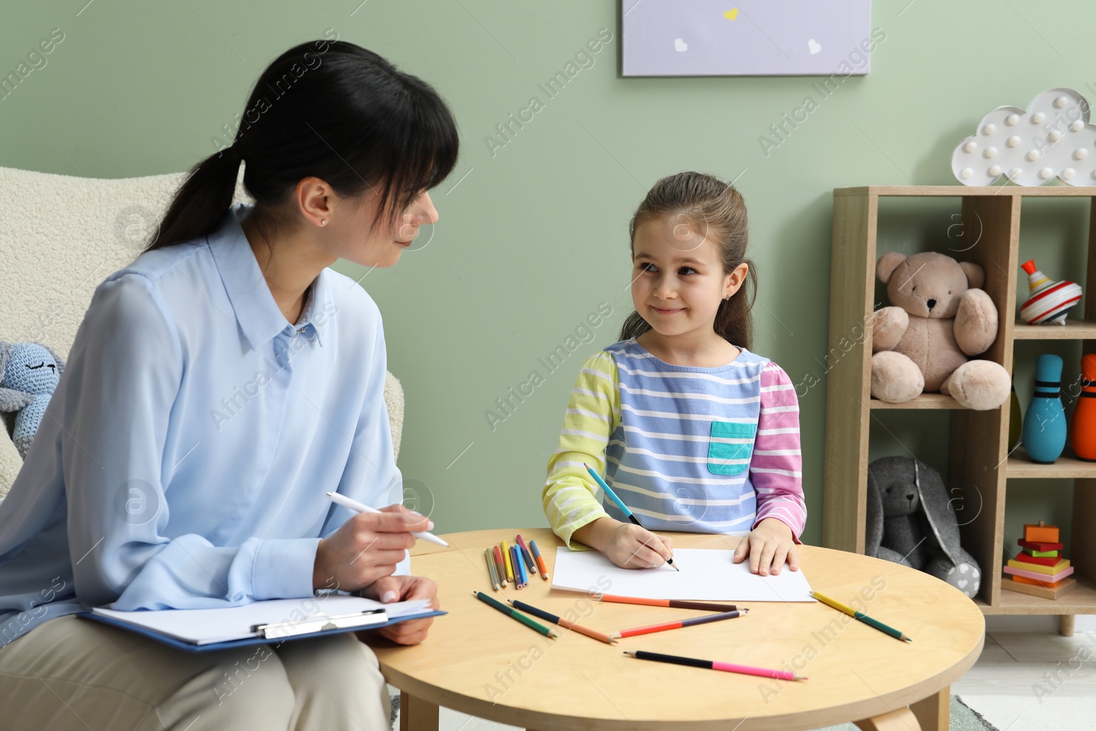 Photo of Little girl drawing during psychological evaluation in office