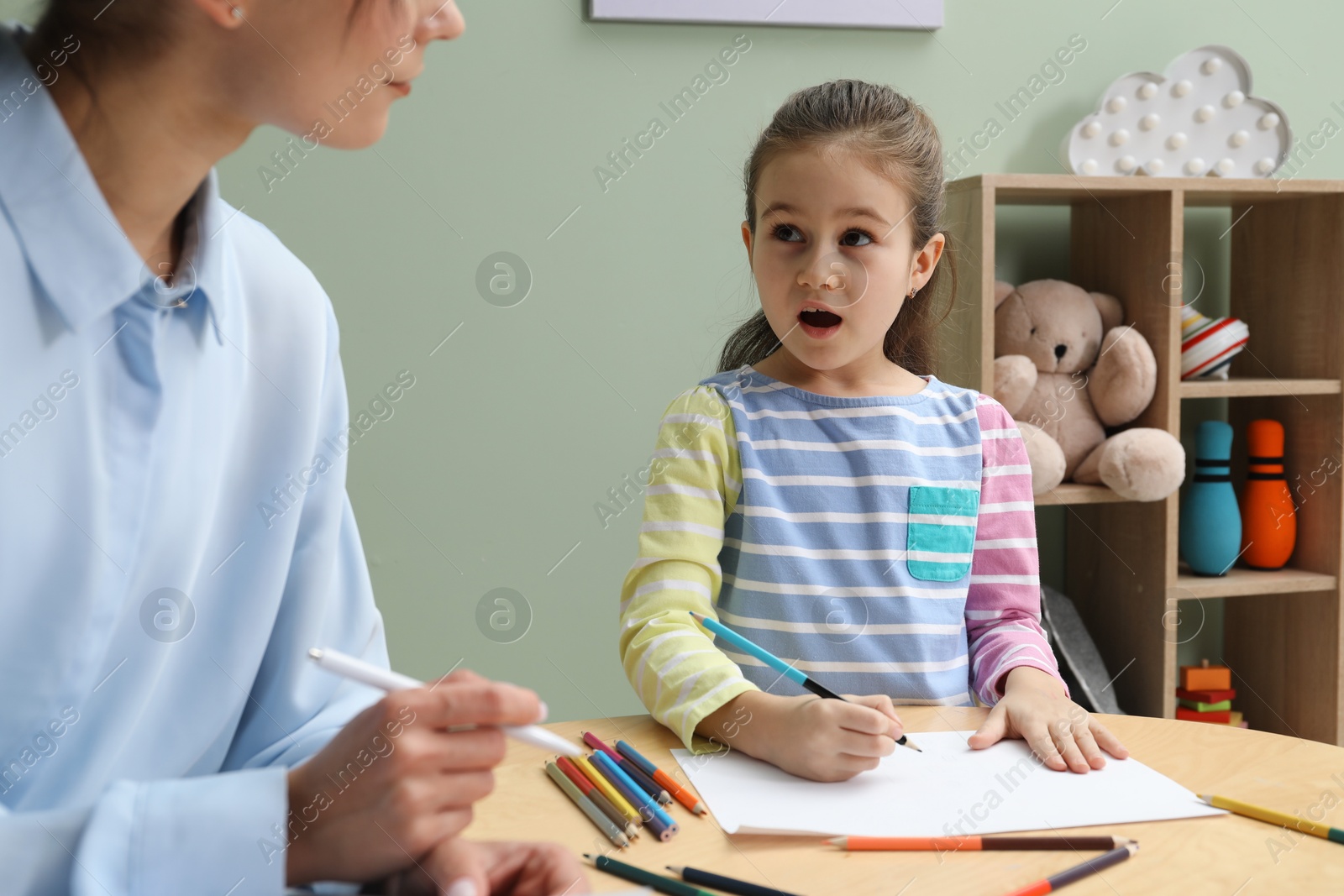 Photo of Little girl drawing during psychological evaluation in office