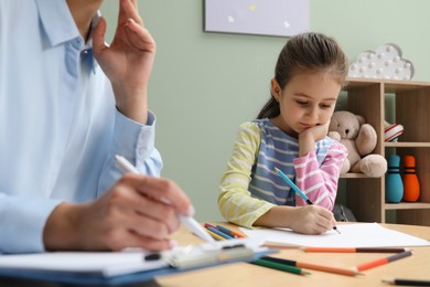 Photo of Little girl drawing during psychological evaluation in office