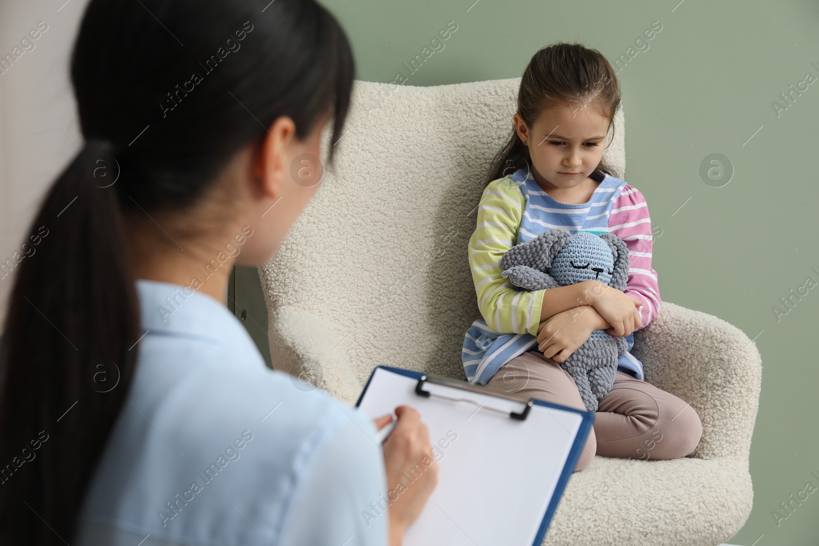 Photo of Psychologist having therapy session with little girl in office, selective focus