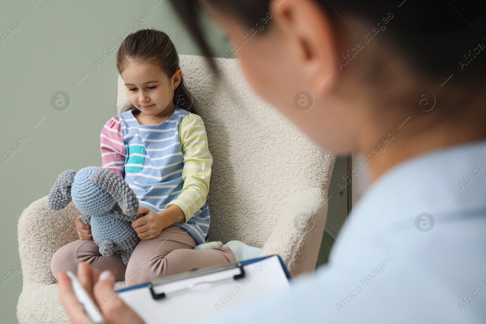 Photo of Psychologist having therapy session with little girl in office, selective focus