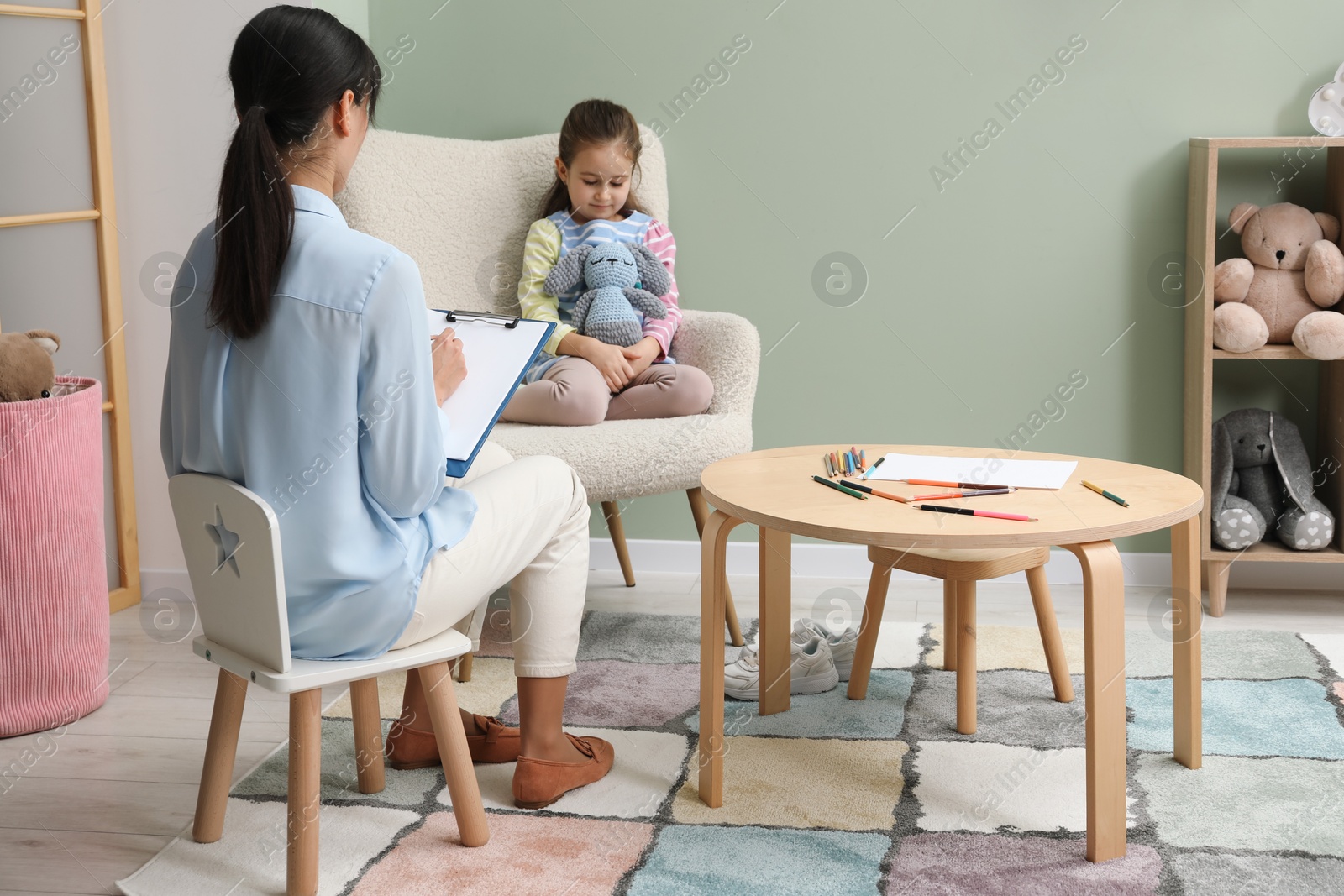 Photo of Psychologist having therapy session with little girl in office