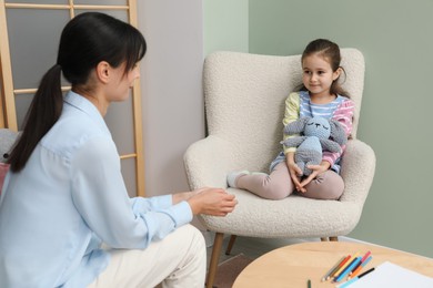 Photo of Psychologist having therapy session with little girl in office