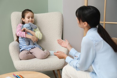 Photo of Psychologist having therapy session with little girl in office