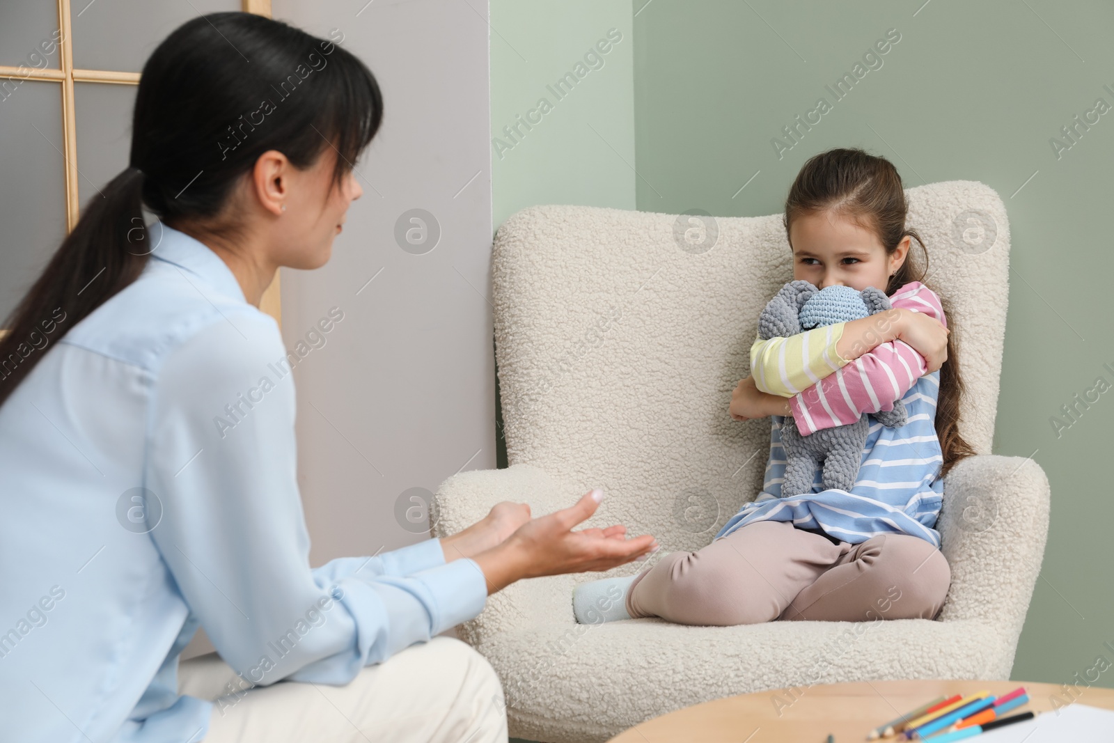 Photo of Psychologist having therapy session with little girl in office