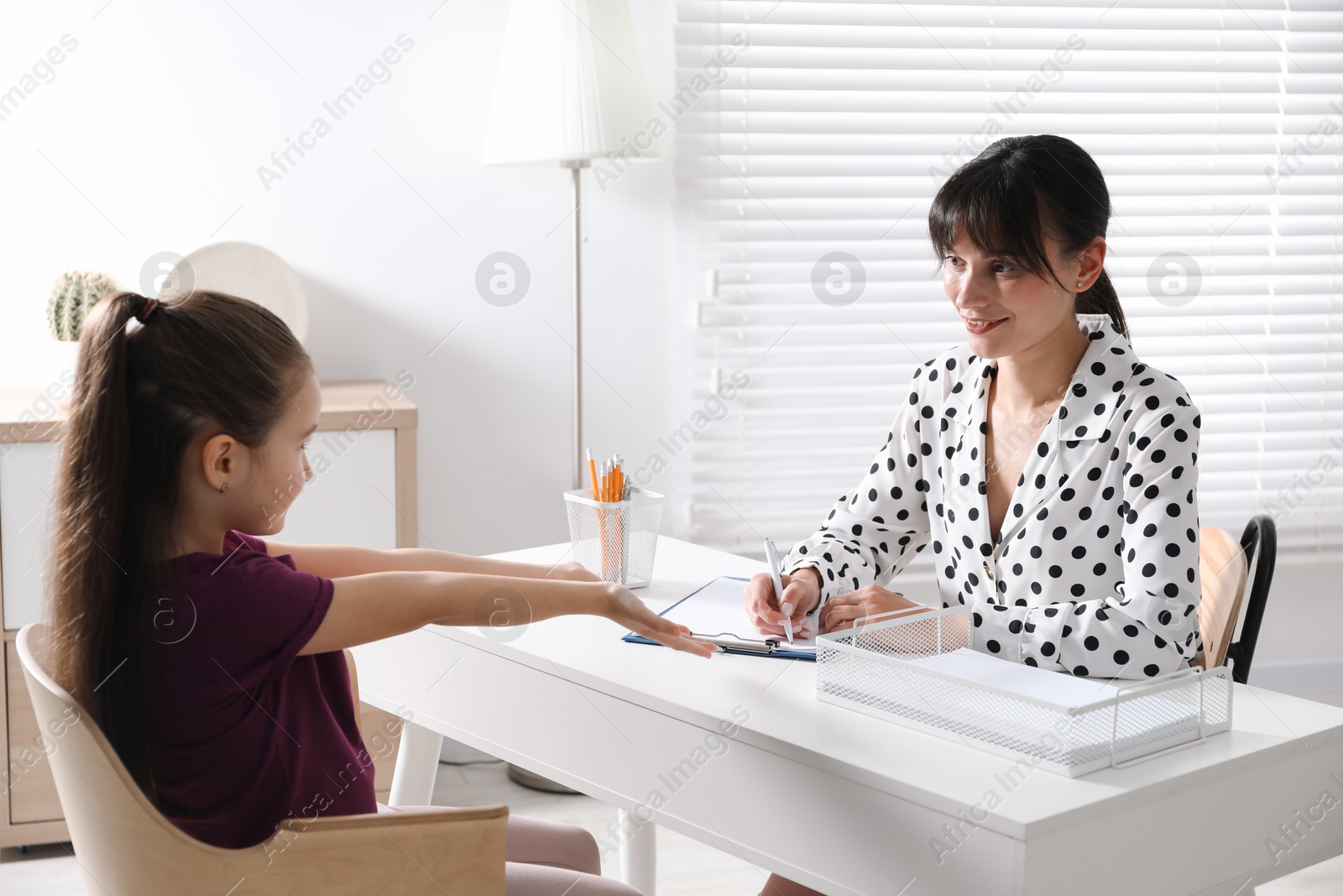 Photo of Psychologist having consultation with girl at desk in office