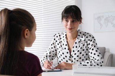 Photo of Psychologist having consultation with girl at desk in office