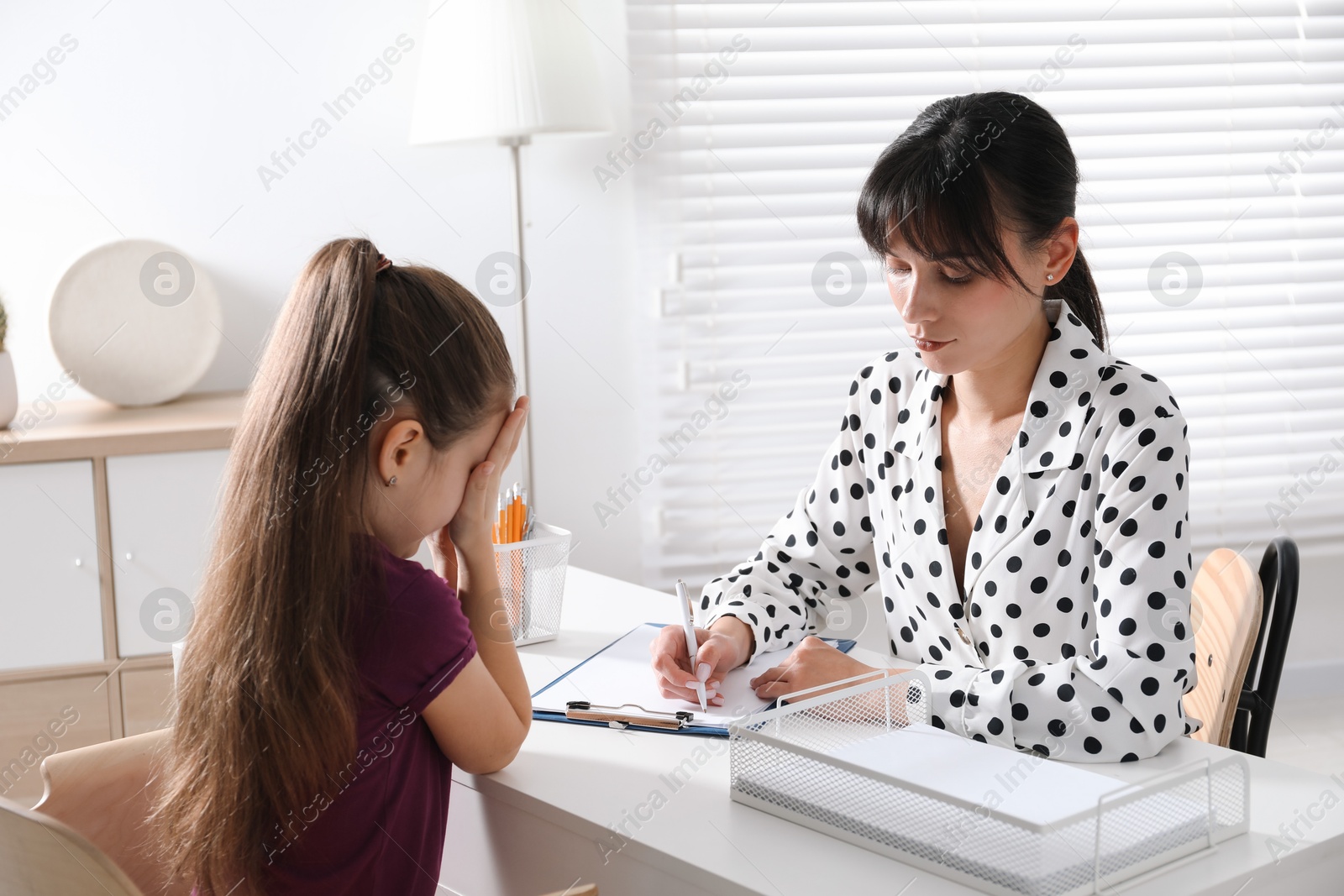 Photo of Psychologist having consultation with girl at desk in office