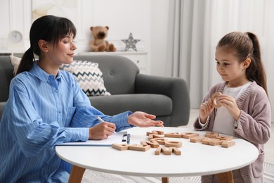 Photo of Psychologist evaluating girl's cognitive functions at table in office