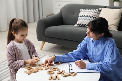 Photo of Psychologist evaluating girl's cognitive functions at table in office