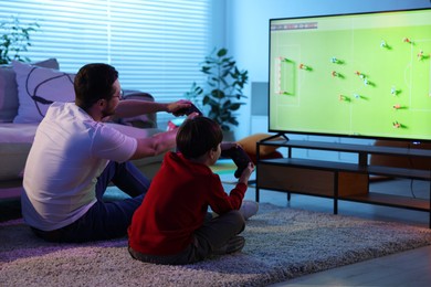 Photo of Father and his son playing video game on floor at home