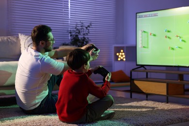 Photo of Father and his son playing video game on floor at home