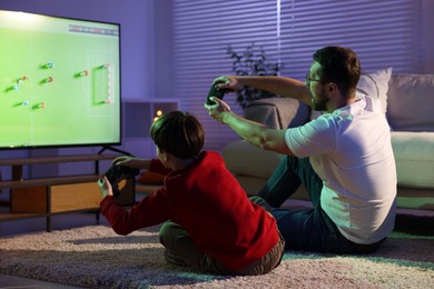 Photo of Father and his son playing video game on floor at home