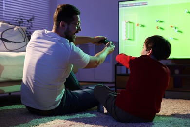 Photo of Father and his son playing video game on floor at home