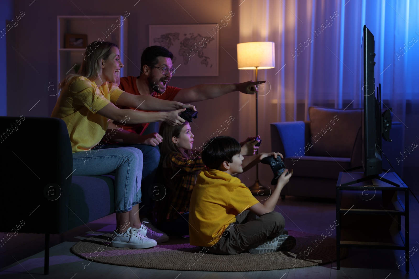 Photo of Happy family playing video games in living room at night