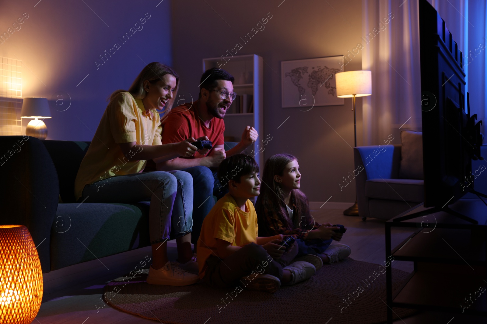 Photo of Happy family playing video games in living room at night