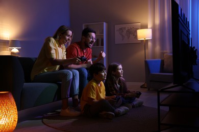 Photo of Happy family playing video games in living room at night