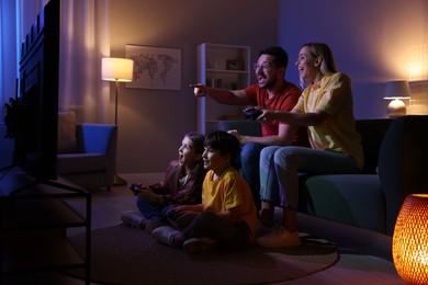 Photo of Happy family playing video games in living room at night