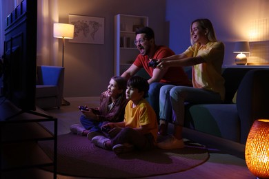 Happy family playing video games in living room at night