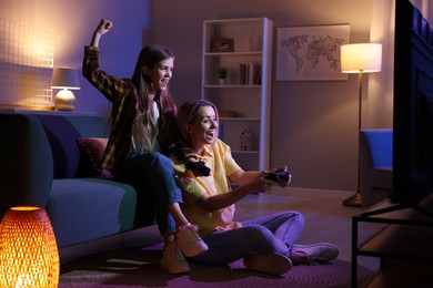 Photo of Happy mother and her daughter playing video games at home