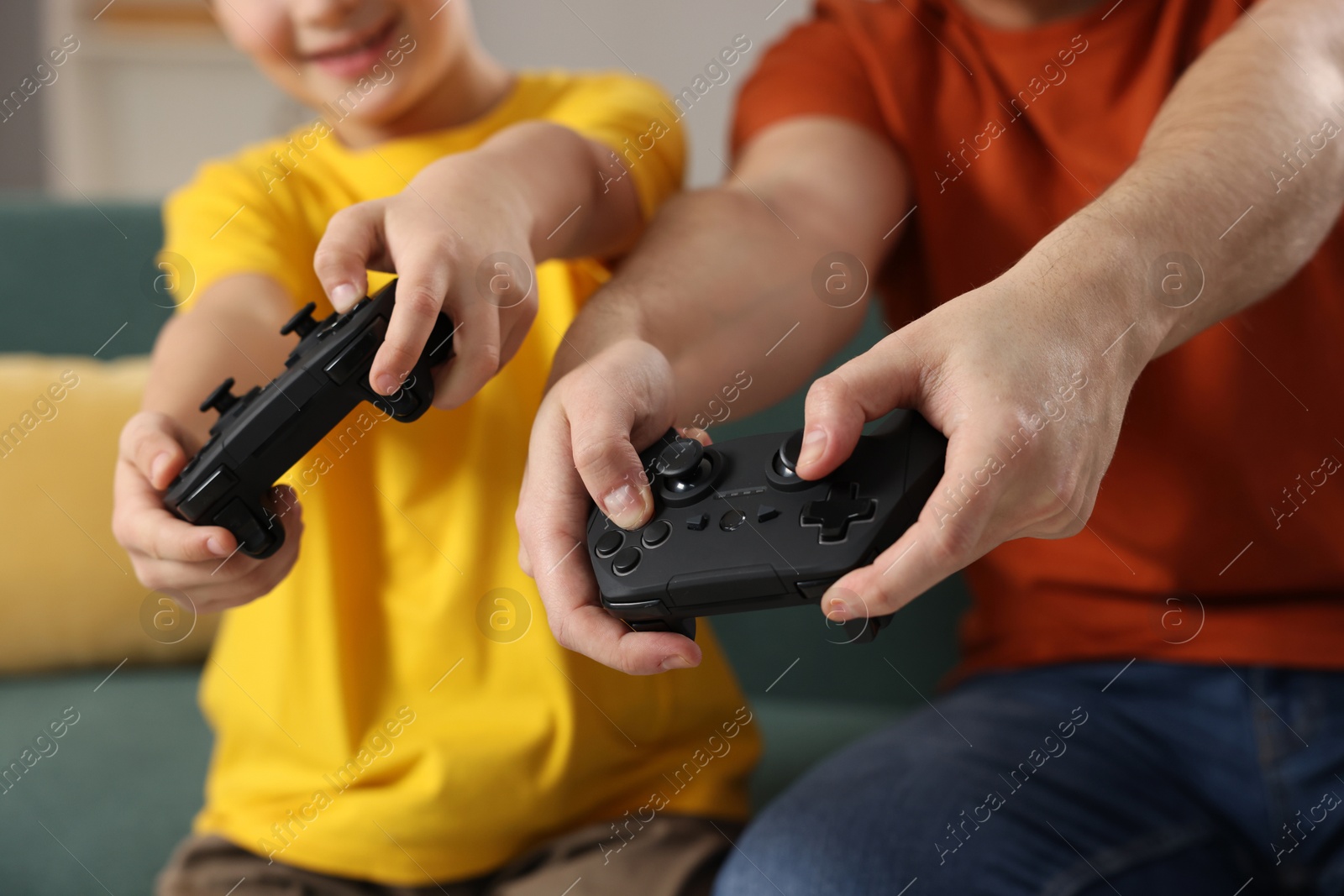 Photo of Father and his son playing video games at home, closeup