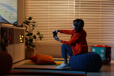 Photo of Little girl in headphones playing video game at home