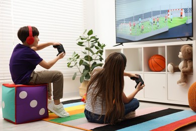 Cute kids in headphones playing video game at home