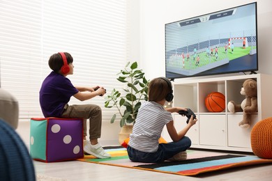 Photo of Cute kids in headphones playing video game at home