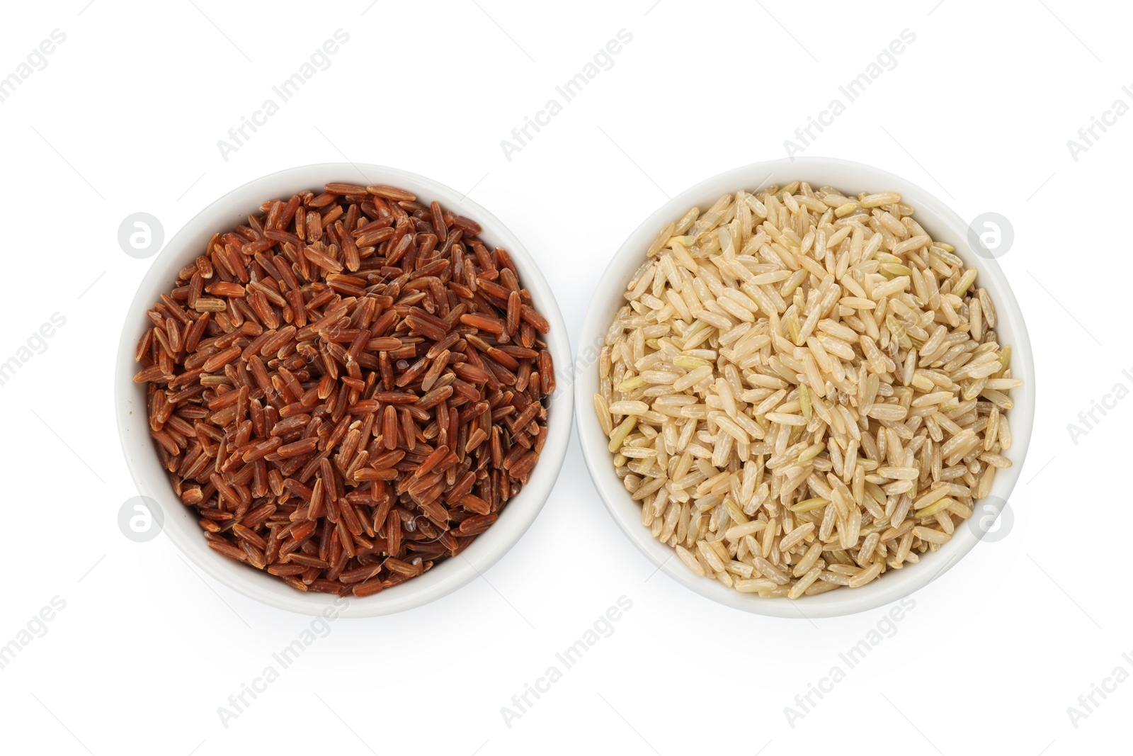 Photo of Different sorts of raw brown rice isolated on white, top view