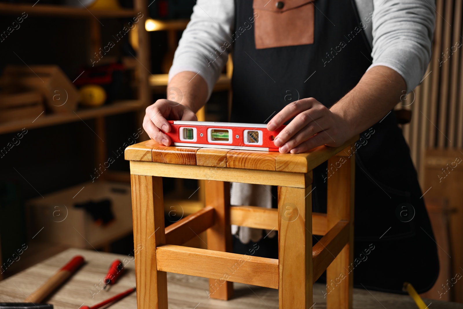 Photo of Repairman checking stool level at table in workshop, closeup