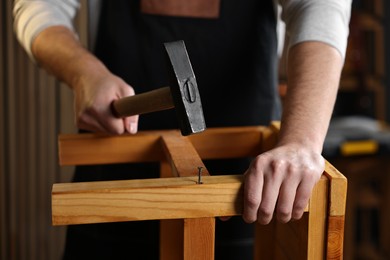 Photo of Carpenter repairing wooden stool in workshop, closeup