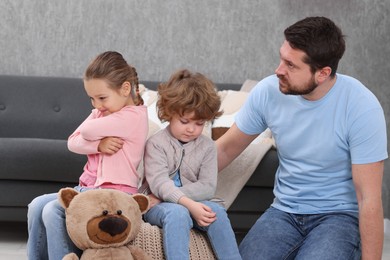 Photo of Resentful little kids and their father arguing at home