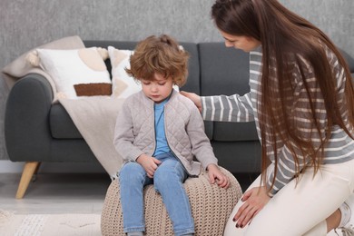 Photo of Resentful little boy and his mother arguing at home