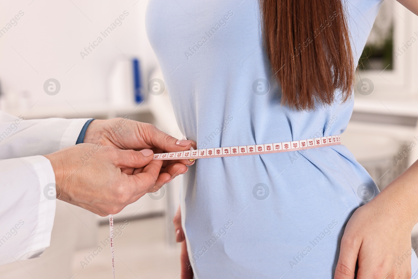 Photo of Weight loss. Nutritionist measuring patient's waist with tape in clinic, closeup