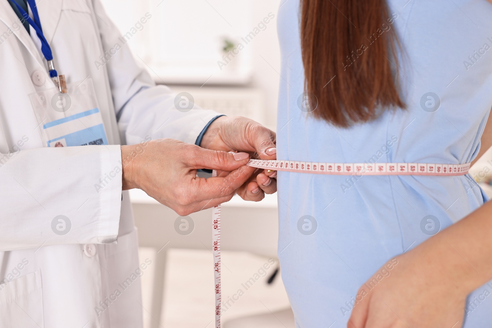 Photo of Weight loss. Nutritionist measuring patient's waist with tape in clinic, closeup