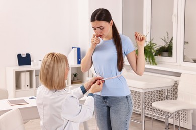 Photo of Weight loss. Nutritionist measuring patient's waist with tape in clinic