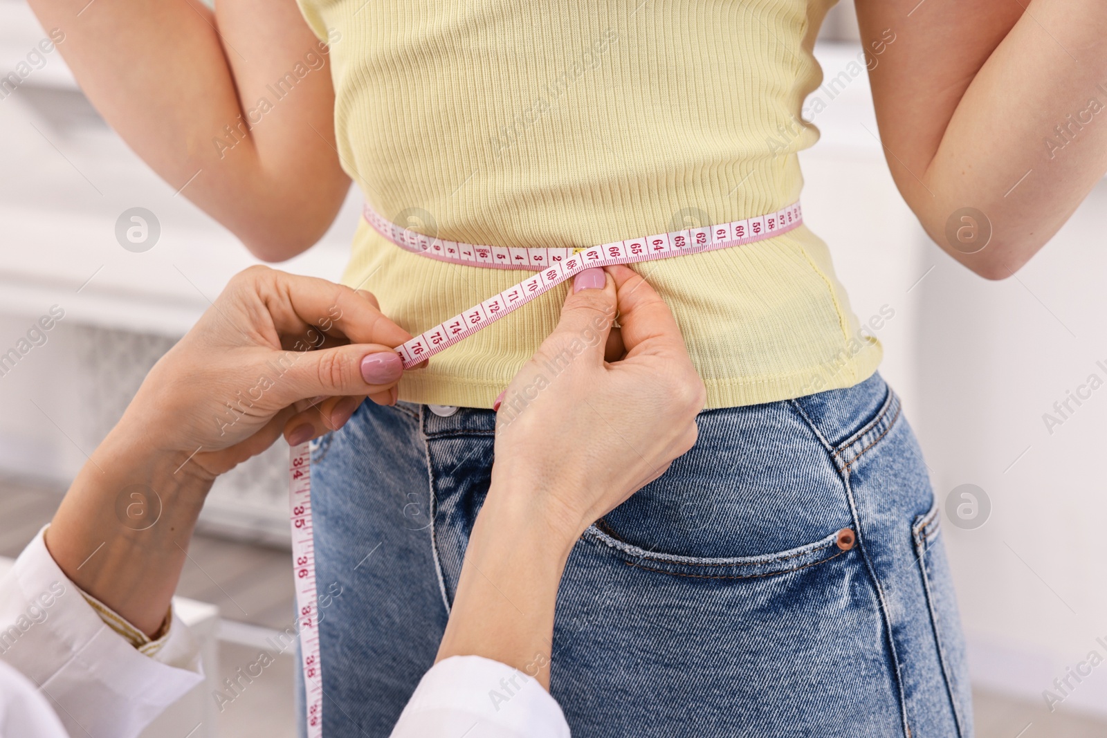 Photo of Weight loss. Nutritionist measuring patient's waist with tape in clinic, closeup