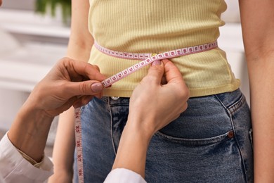 Photo of Weight loss. Nutritionist measuring patient's waist with tape in clinic, closeup