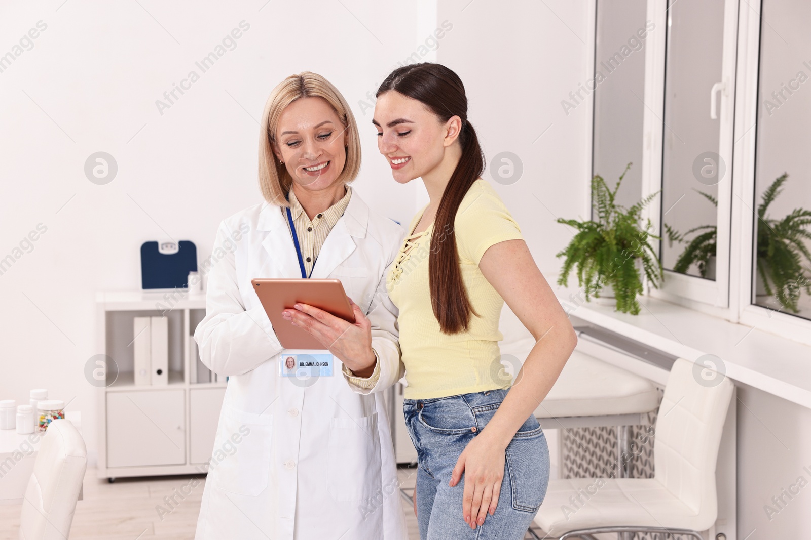 Photo of Weight loss. Smiling nutritionist with tablet consulting patient in clinic