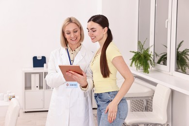 Photo of Weight loss. Smiling nutritionist with tablet consulting patient in clinic