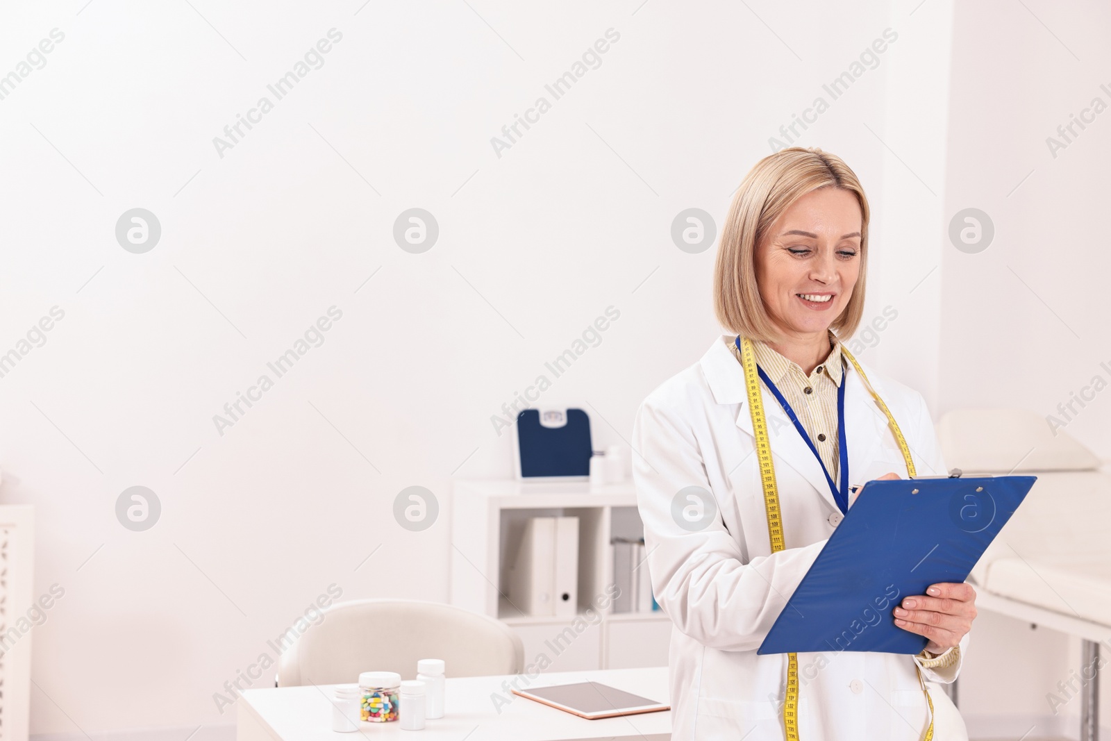 Photo of Weight loss. Happy nutritionist with clipboard in clinic, space for text