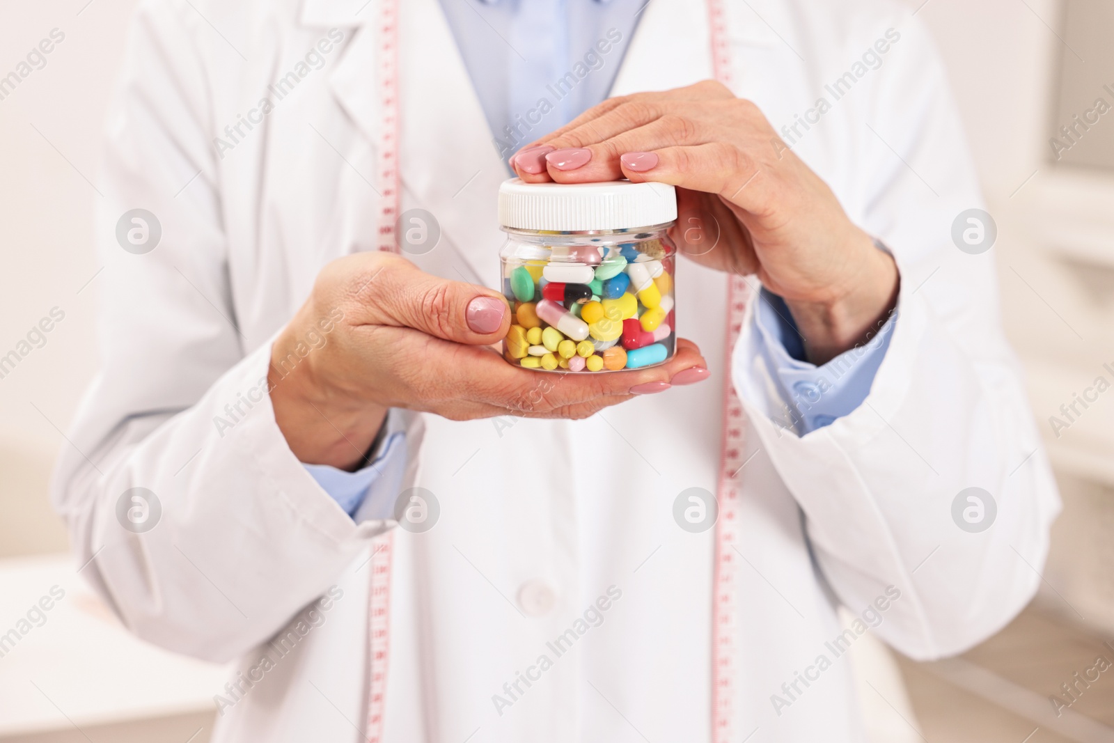 Photo of Nutritionist with bottle of weight loss pills in clinic, closeup