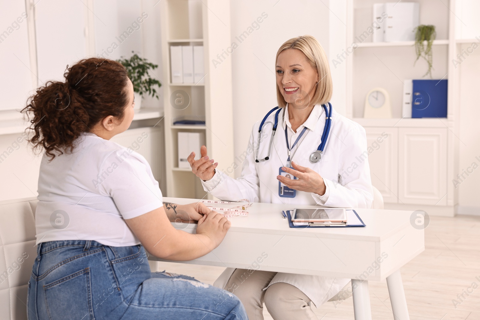 Photo of Weight loss. Smiling nutritionist consulting patient at table in clinic