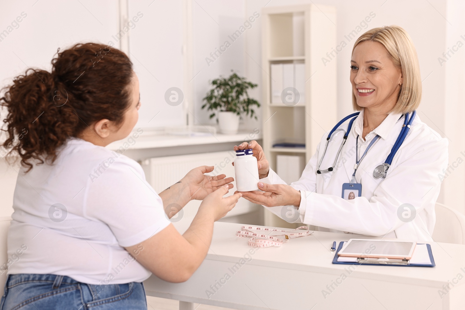 Photo of Weight loss. Smiling nutritionist consulting patient at table in clinic