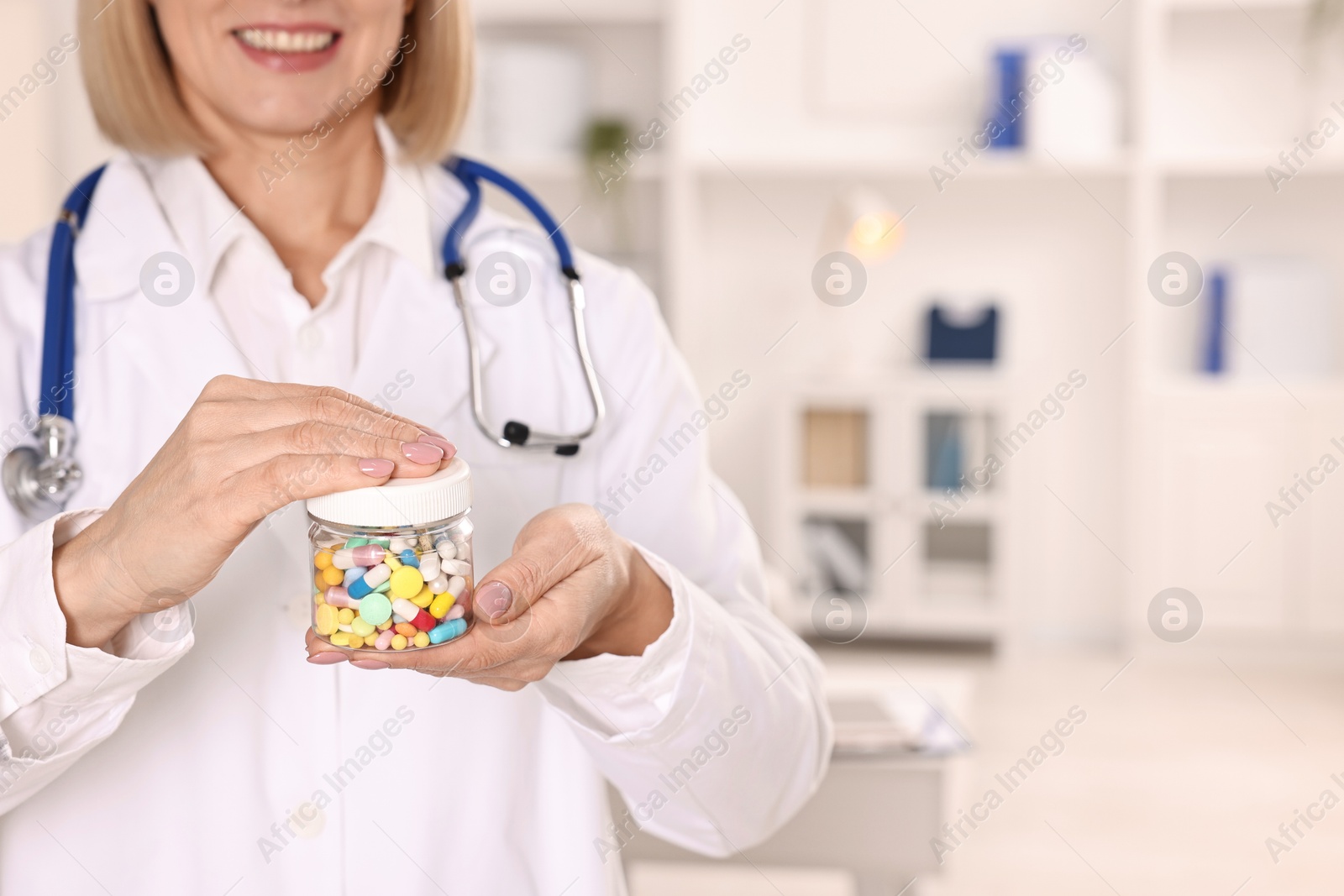 Photo of Happy nutritionist with container of weight loss pills in clinic, closeup. Space for text