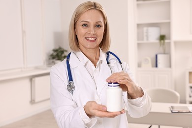 Photo of Happy nutritionist with bottle of weight loss pills in clinic