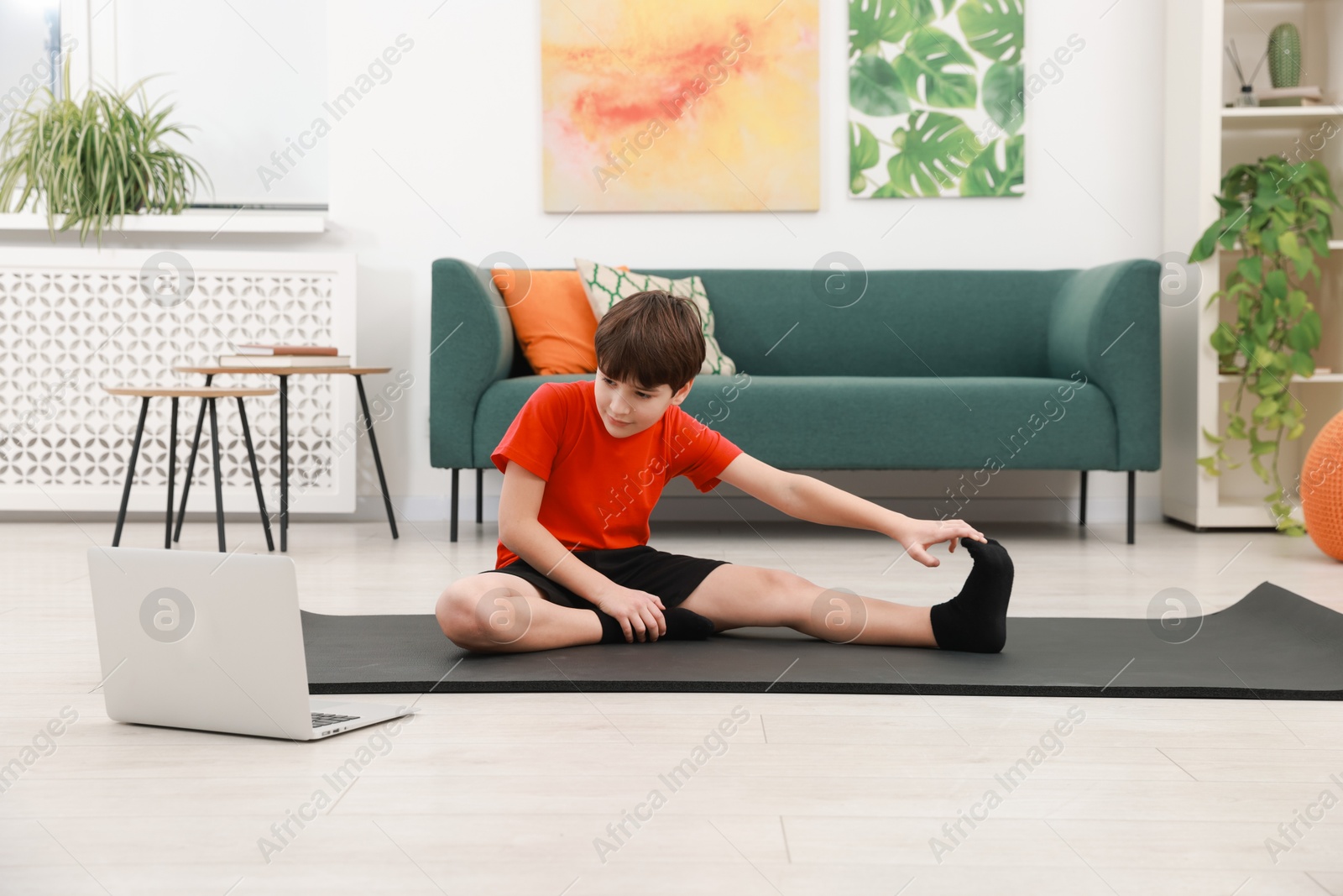 Photo of Boy having training with online coach via laptop at home