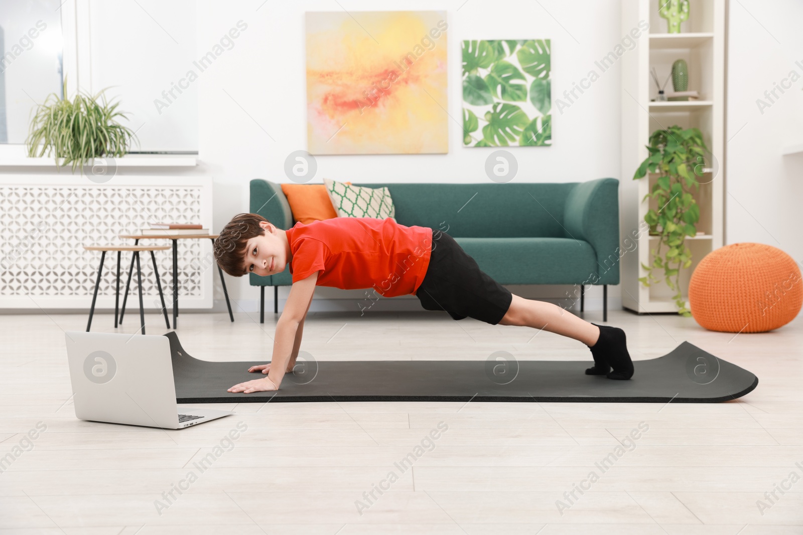 Photo of Boy having training with online coach via laptop at home